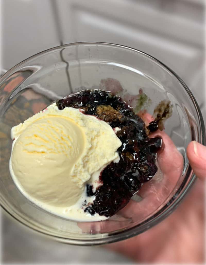 A bowl of freshly baked berry cobbler with ice cream